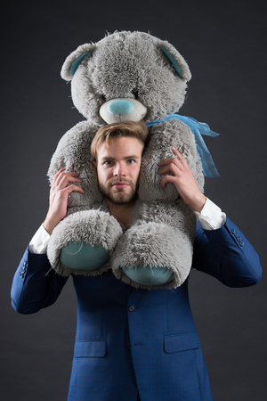 Bearded man with grey teddy bear. Businessman hold big animal toy. Fashion manager with toy gift or present. Birthday or anniversary and holiday celebration.の写真素材