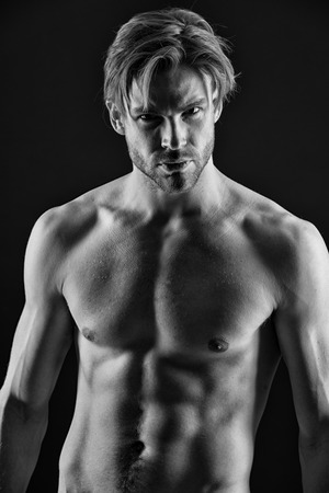 Bearded man athlete with fit torso. Bodybuilder with sexy chest and belly. Sportsman show muscles. Workout and training activity in gym. Sport or bodybuilding and fitness concept, black and white.の写真素材