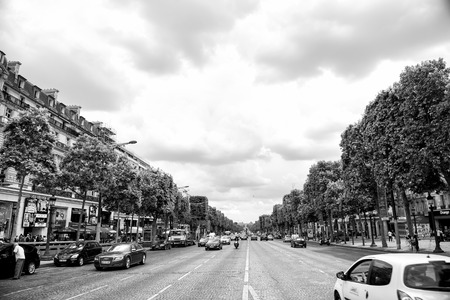 Paris, France - June 02, 2017: Elysian Fields avenue with street traffic and green trees on cloudy sky background. Landmark and sightseeing. Summer vacation and travel concept, triumphal arch roadのeditorial素材