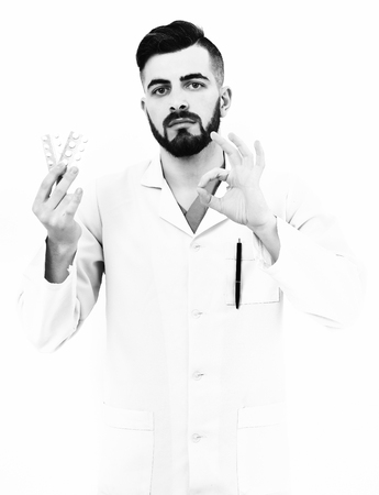 Doctor with beard holds pills blisters and shows ok signの写真素材