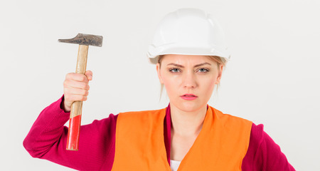 Girl in helmet or hard hat raise up hammer.の写真素材