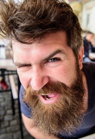 Guy having rest at cafe terrace, close up. Man with beard and mustache in good mood while relaxing at cafe terrace. Hipster, client, visitor on happy face sits at cafe outdoor. Bearded macho conceptの写真素材