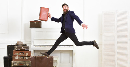 Long awaited vacation concept. Macho attractive, elegant on cheerful face carries vintage suitcases,...