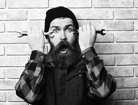 Bearded brutal caucasian mechanic holding metallic wrenchesの写真素材