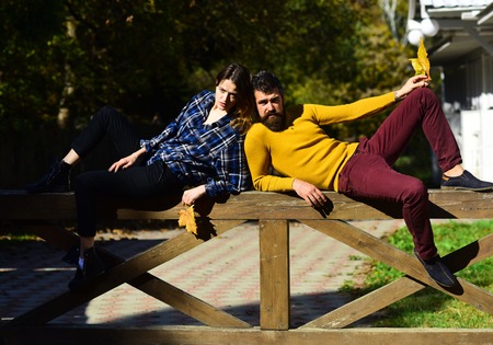 Girl and bearded guy lie on handrail back to back.の写真素材