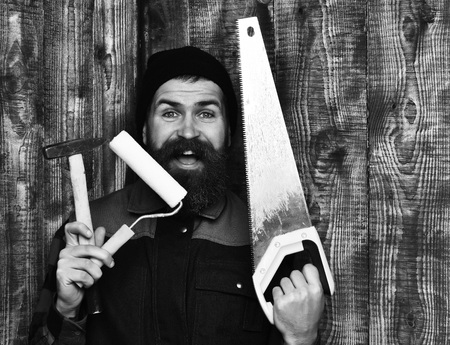 bearded builder holding various building tools with happy faceの写真素材