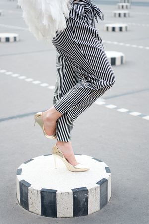 Fashion accessory style and vogue concept. Legs in glamour golden shoes paris, france. High heel shoes on female feet on city square. Fashion shoes on column outdoor. luxury and trendy look conceptの写真素材
