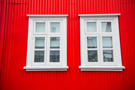 Windows in house in reykjavik, iceland. Building facade with red wall and white window frames. Architecture structure and design.の写真素材
