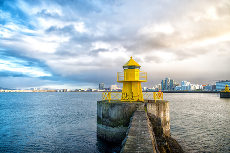 Lighthouse tower on stone pier in reykjavik, iceland. Lighthouse in sea. Seascape and skyline on cloudy sky. Architecture structure and design. Navigational aid concept. Wanderlust and travelling.の写真素材