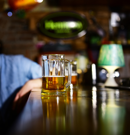 Glass of light beer on wooden bar counter.の写真素材