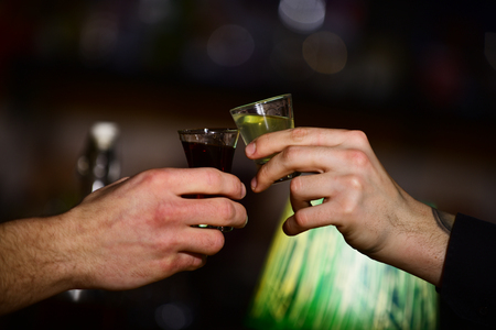 Male hands cheers with alcohol on blurred bar background.の写真素材
