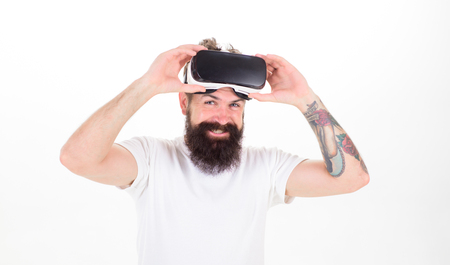 Man with beard and mustache holds VR glasses, white background. VR technology concept. Guy with VR glasses or head mounted display. Hipster on smiling face use modern technologies for entertainmentの写真素材