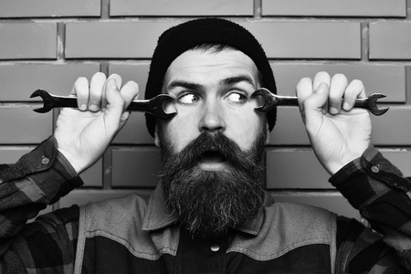 Bearded brutal caucasian mechanic holding metallic wrenchesの写真素材