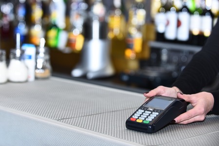Electronic finance and shopping. Cashiers hand holds credit card readerの写真素材