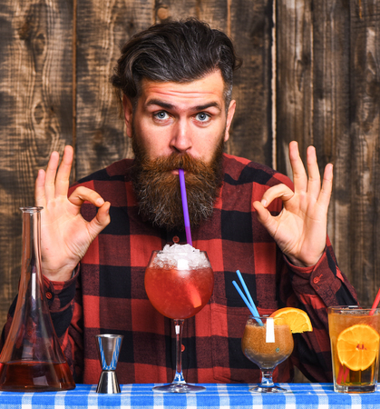 Man shows ok gesture on wooden background. Alcohol and cocktails