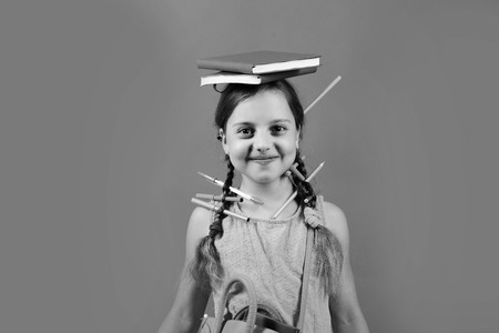 Girl holds red and blue books on headの写真素材