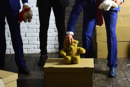 Men put teddy bear on carton box. Business and charity