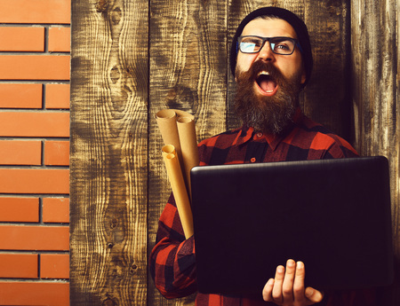 Bearded brutal caucasian hipster holding laptop and craft paperの写真素材