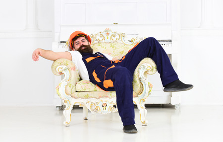 Bearded worker lying in vintage armchair isolated on white background. Tired mover enjoying short breakの写真素材