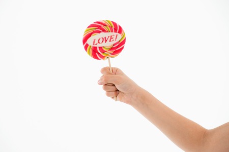 Lollipop with love lettering isolated on white. Candy on stick in hand. Sweet candy swirl. Valentines day concept. Food and dessert eating, copy space. Lollipop fun.の写真素材