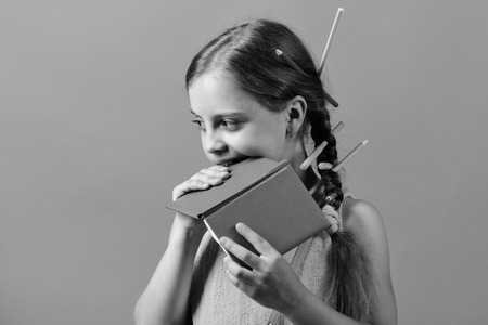 Kid in pink blouse with braids and pencils in themの写真素材