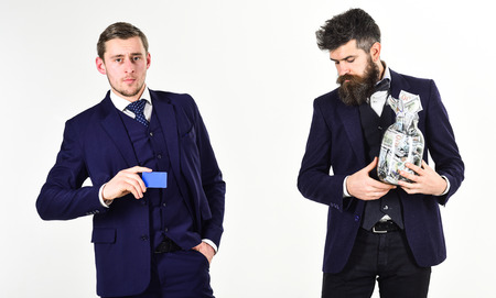 Men in suit, businessmen with jar full of cash and credit card, white background. Mature man prefers cash, modern guy recommends credit card, electronic money, copy space.の写真素材
