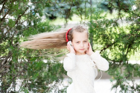 Girl dance to music in summer park. Small child enjoy music in headphones outdoor. Kid dancer with long flying hair. Melody sound and mp3. Summer fun and joyの写真素材