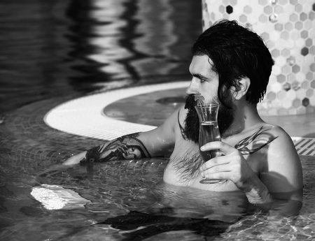 Man drinks cocktail in poolの写真素材