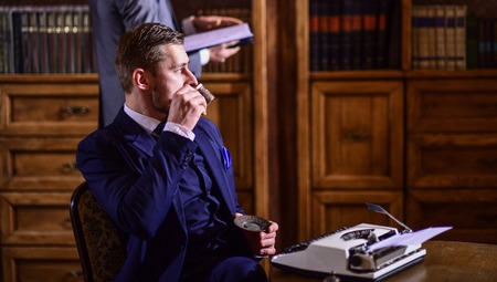 Men in suits in library with antique books on background.の写真素材