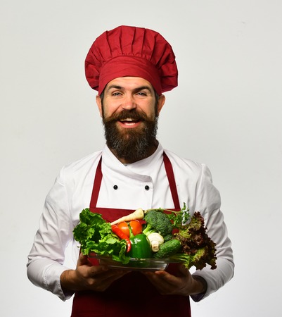 Man with beard isolated on white background. Chef holds vegetables.の写真素材