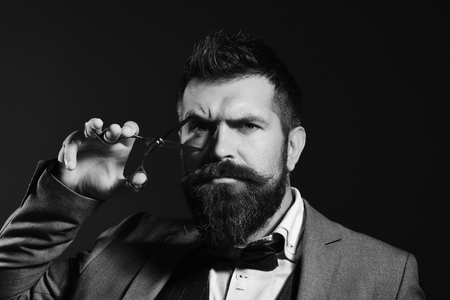 Barber shop. Hair style. Man with long beard holds steel scissors.の写真素材