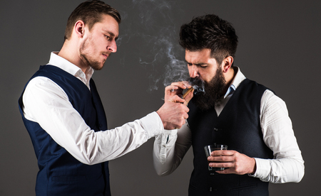 Friend, business partner, assistant helping man with beard light cigar.の写真素材