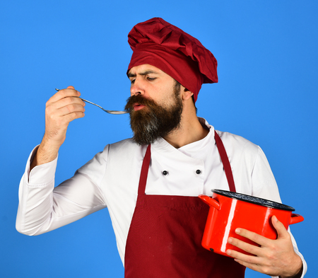 Chef with red saucepan and cutlery. Man with beardの写真素材