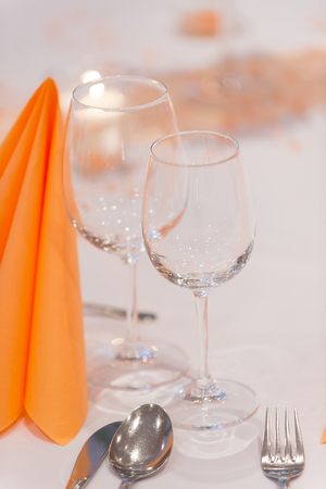 Wineglasses and folded table napkin tishue on restaurants table covered with white tablecloth. Cutlery and wineglasses served in restaurant, close up. Restaurant service conceptの写真素材