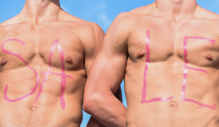 Chests of sexy muscular athletes, nude torsosand sky on background. Inscription sale on sexy muscular chests. Muscular torsos of strong sportsmen with word sale written on. Sale conceptの写真素材
