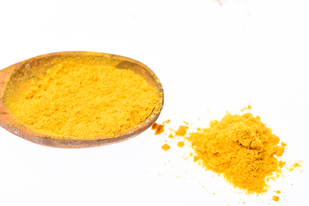 Spoon filled with ground curcuma powder. Condiments and spices concept. Spoon with spice as curcuma, yellow powder on white background, close up. Spoon made out of wood full of spiceの写真素材
