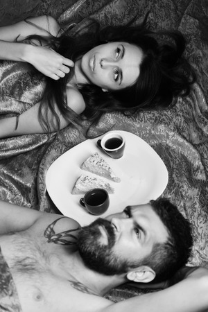 Couple in love on red sheets. Man with beardの写真素材