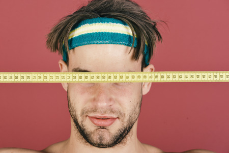athlete in training. Man with messy hair has eyes closed with measure tapeの写真素材