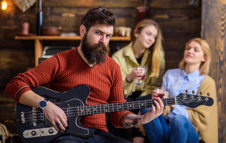 Guitarist rehearsing new show. Bearded man entertaining his wife and daughter with lovely tunes. Rock musician on vacation with family in countryside. Man with stylish hipster beard playing guitarの写真素材