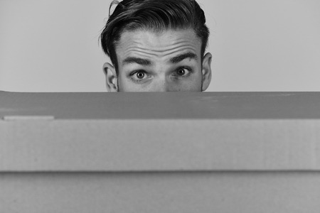 Man hiding behind cardboard box on grey backgroundの写真素材