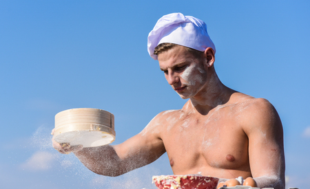 Baker working with flour and sieve, kneading dough. Hands of chef cook covered with sticky dough and flour. Pizzaiolo concept. Man muscular baker or cook sifts flour through sieveの写真素材
