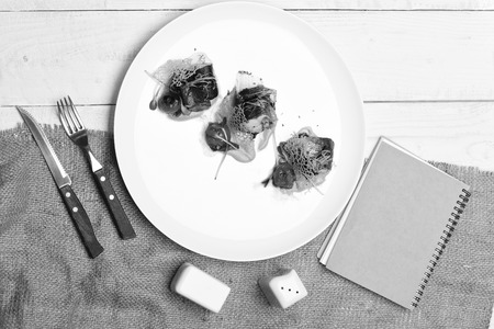 Sophisticated restaurant dish near fork, spoon, notebook, , salt and pepper.の写真素材