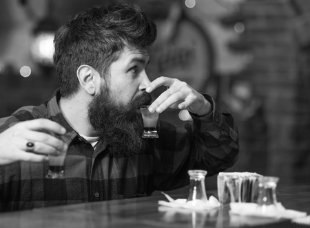 handsome visitor sit at bar counter and holds shot drinks.の写真素材