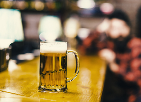 Glass filled with cold tasty beer in pub.の写真素材