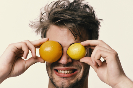 Man with orange and lemon instead of eyes in handsの写真素材
