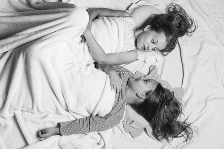 Schoolgirls have rest in bed looking at each other.の写真素材