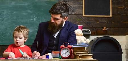 Excited kid showing daddy what he drew. Concentrated father checking the artwork of his sonの写真素材