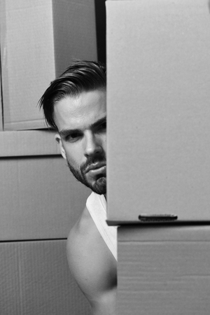 Macho with beard and concerned face hiding among boxesの写真素材