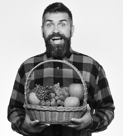 Man with beard holds fruit basket with fruit, white backgroundの写真素材