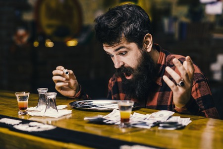 bar drinking. shocked man at table with alcohol drinks, moneyの写真素材